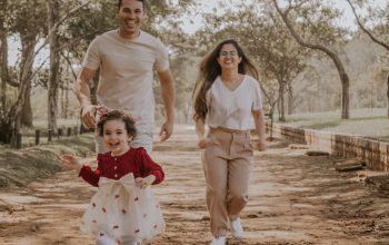 Smiling family enjoys a playful walk in a São Paulo park during a sunny day.